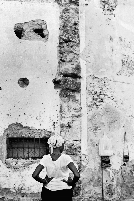 Black and white image of a woman with her back to the camera, hands on her hips.